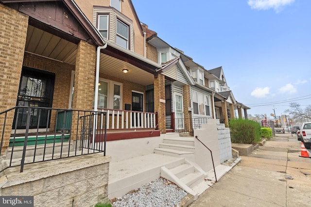 property entrance with brick siding, a residential view, and a porch