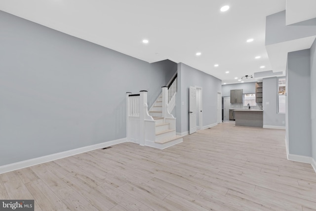 unfurnished living room with recessed lighting, stairway, light wood-style flooring, and baseboards