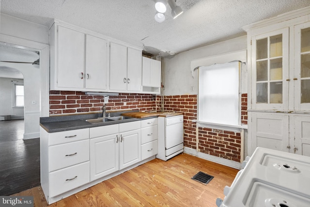kitchen with a sink, visible vents, light wood-type flooring, and white cabinetry