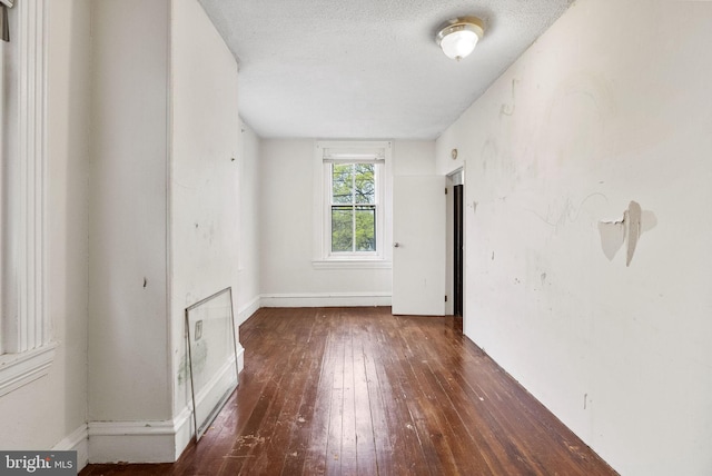 empty room featuring baseboards, hardwood / wood-style floors, and a textured ceiling