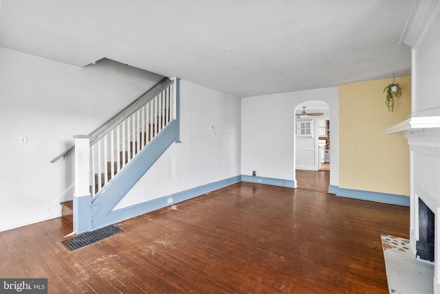 unfurnished living room featuring baseboards, stairway, a ceiling fan, a fireplace with flush hearth, and hardwood / wood-style flooring