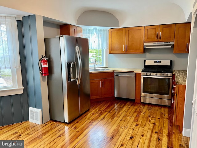kitchen with visible vents, a sink, under cabinet range hood, stainless steel appliances, and hardwood / wood-style floors