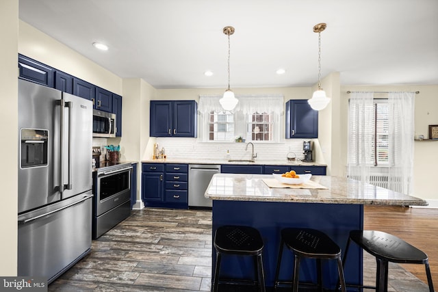 kitchen with blue cabinetry, a sink, light countertops, a breakfast bar, and stainless steel appliances