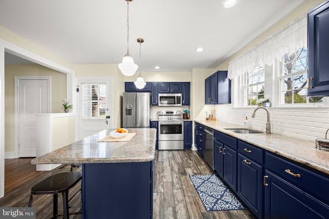 kitchen featuring a kitchen island, a breakfast bar, blue cabinets, a sink, and appliances with stainless steel finishes
