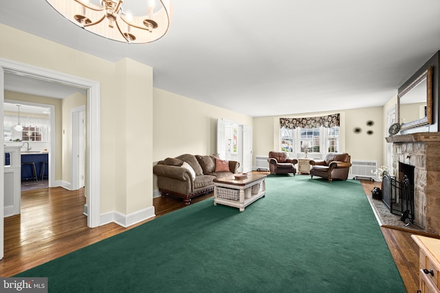 living room with a fireplace, a notable chandelier, radiator, and dark wood-type flooring
