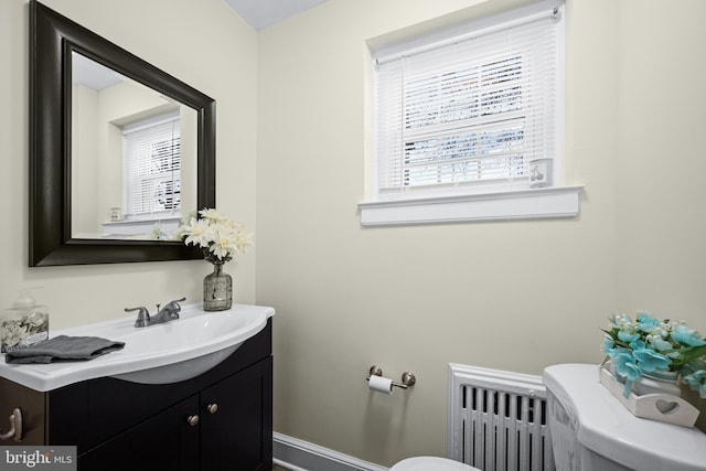 bathroom featuring vanity, radiator, baseboards, and toilet