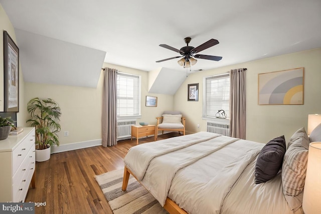 bedroom with wood finished floors, baseboards, radiator heating unit, and vaulted ceiling