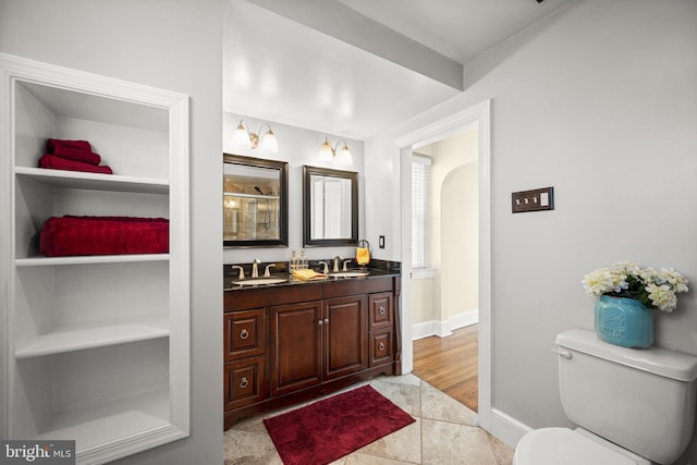 full bath featuring double vanity, toilet, baseboards, and a sink