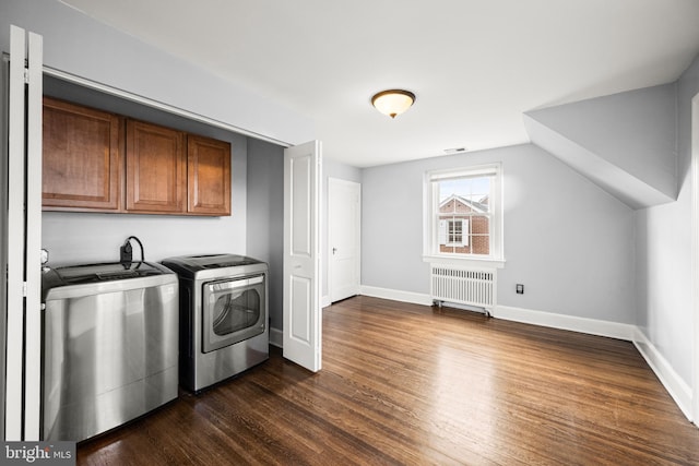 laundry room featuring cabinet space, dark wood-type flooring, radiator, and washer and dryer