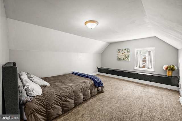 carpeted bedroom featuring baseboards and lofted ceiling
