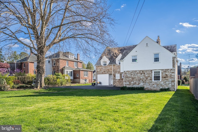 exterior space with fence, a chimney, a yard, and stone siding