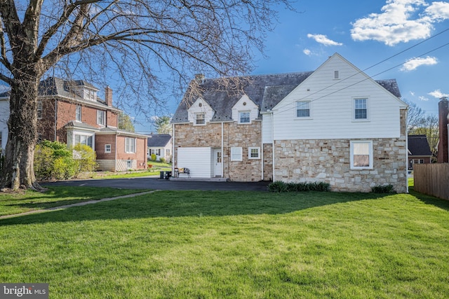 exterior space with a front lawn, fence, and stone siding