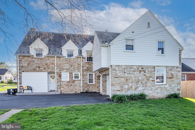 back of house featuring a lawn, fence, central AC, and stone siding