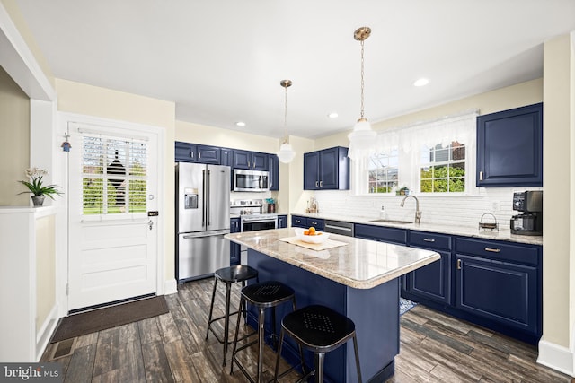 kitchen with stainless steel appliances, dark wood finished floors, a sink, and blue cabinets