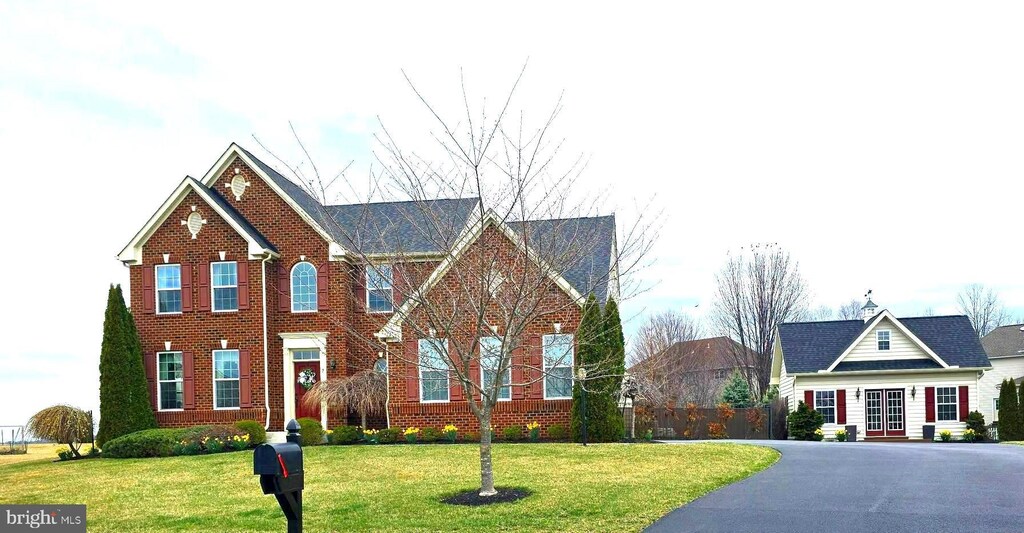traditional-style house with brick siding, a front lawn, and aphalt driveway