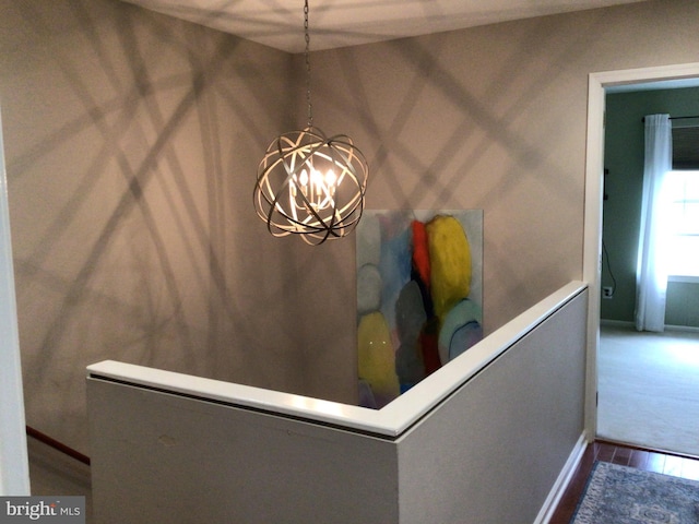 interior details with wood finished floors, a chandelier, and baseboards