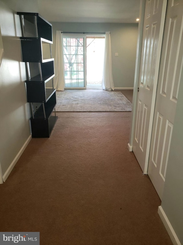 hall featuring baseboards and carpet