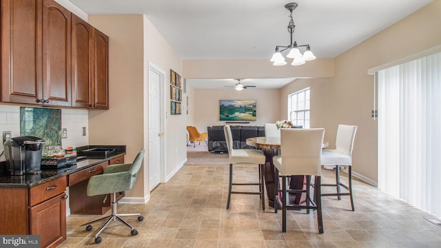 dining room with baseboards, ceiling fan with notable chandelier, and built in desk