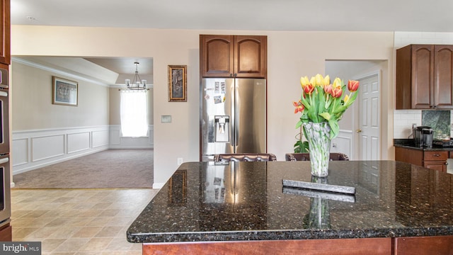 kitchen with dark stone counters, a center island, stainless steel appliances, and a notable chandelier