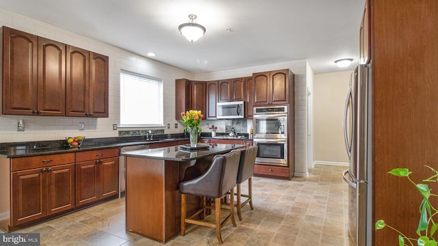 kitchen featuring decorative backsplash, a kitchen island, a kitchen bar, dark stone counters, and stainless steel appliances