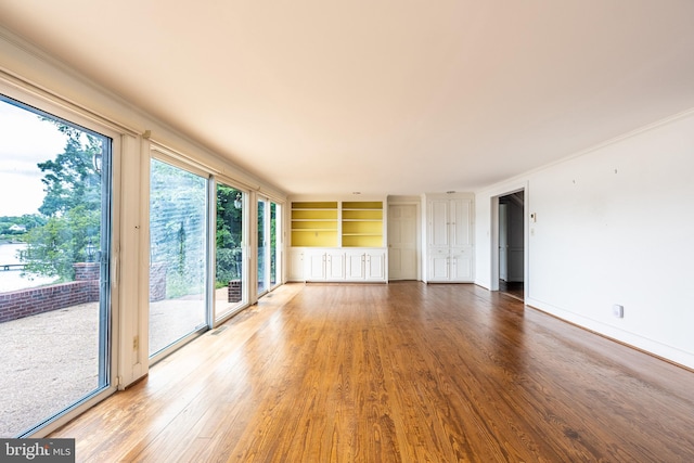 391 Steamboat Rd, Irvington, VA 22480 - interior space featuring crown molding, built in shelves, wood finished floors, and baseboards