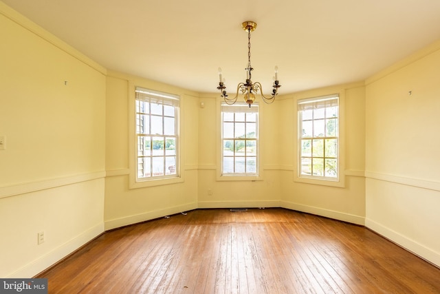 391 Steamboat Rd, Irvington, VA 22480 - empty room featuring wood-type flooring, baseboards, and an inviting chandelier