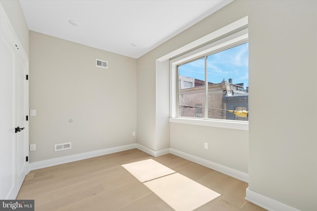 unfurnished room featuring visible vents, baseboards, and wood finished floors