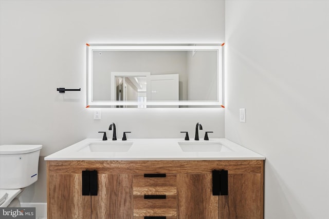 bathroom with toilet, double vanity, and a sink