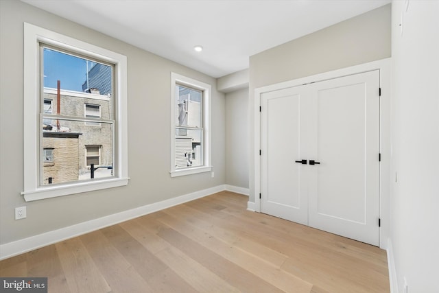 unfurnished bedroom with light wood-type flooring, a closet, baseboards, and recessed lighting
