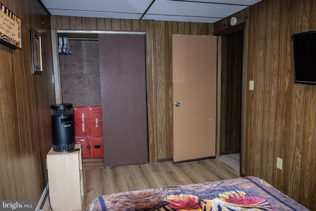 bedroom with wood walls, a closet, and wood finished floors