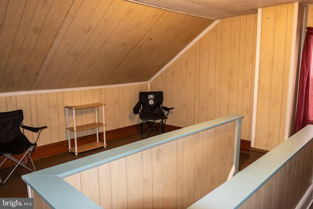 interior space featuring wooden walls, an upstairs landing, wooden ceiling, and vaulted ceiling