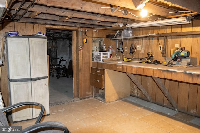 unfinished below grade area featuring wooden walls and a workshop area