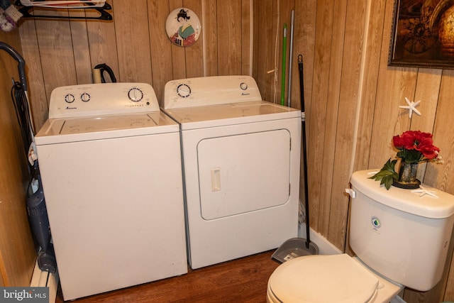clothes washing area featuring washer and dryer, laundry area, wood finished floors, and wood walls