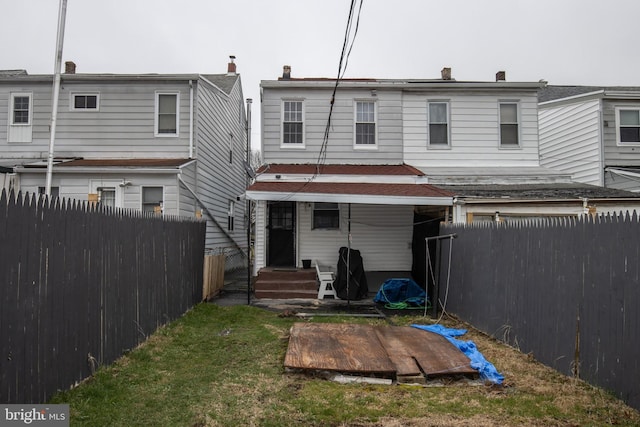 rear view of house featuring a fenced backyard