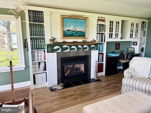 living area with wood finished floors, a fireplace, baseboards, and a healthy amount of sunlight