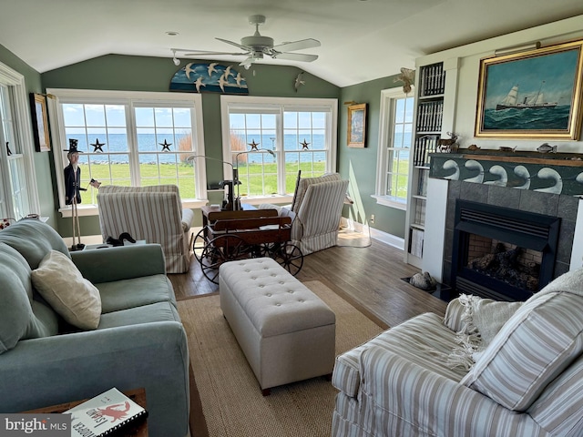 living room featuring baseboards, a tiled fireplace, ceiling fan, wood finished floors, and lofted ceiling