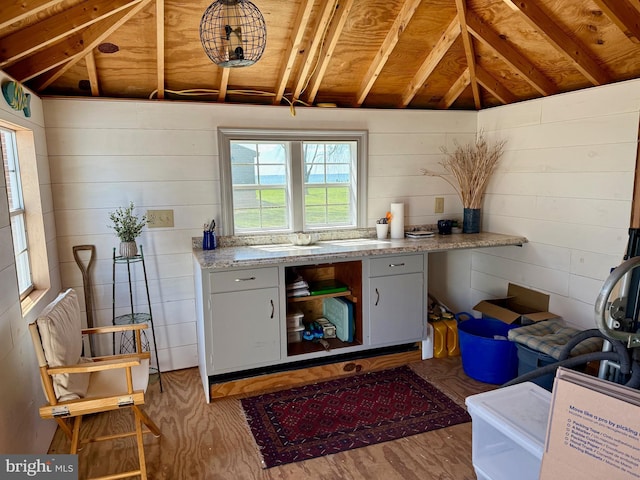 interior space featuring wood finished floors, wood walls, and lofted ceiling