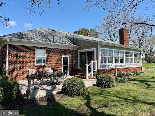 back of property featuring a patio, roof with shingles, brick siding, a sunroom, and a lawn