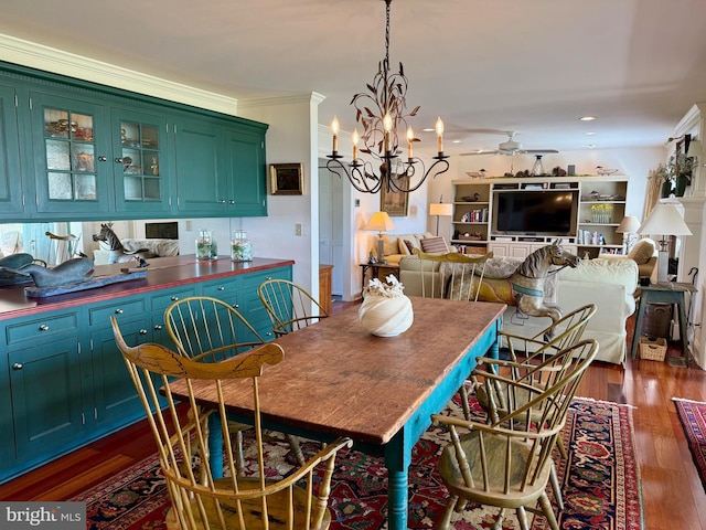 dining space with crown molding, ceiling fan with notable chandelier, and dark wood-style flooring