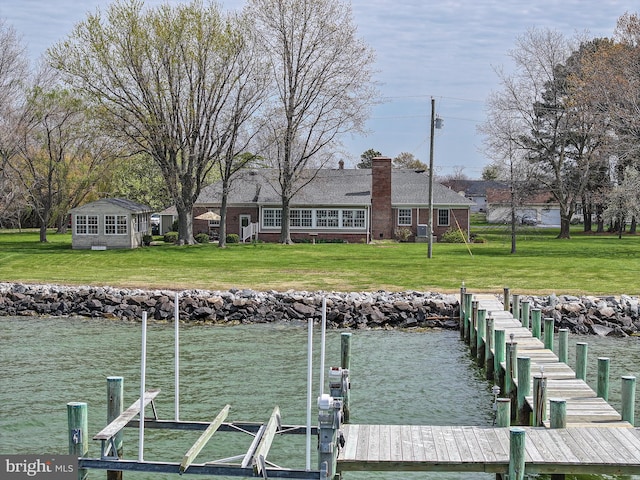 view of dock with a water view and a lawn