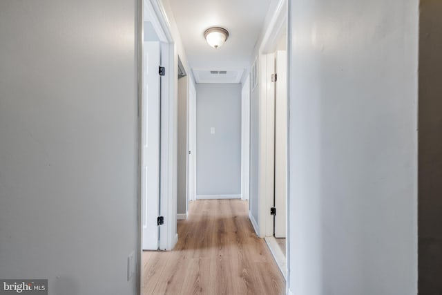 hall featuring light wood-style flooring and baseboards