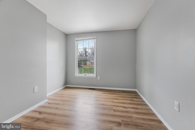spare room featuring visible vents, baseboards, and wood finished floors
