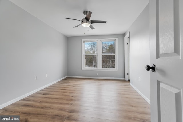 empty room with baseboards, wood finished floors, and ceiling fan