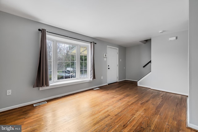 interior space featuring stairway, baseboards, visible vents, and hardwood / wood-style flooring