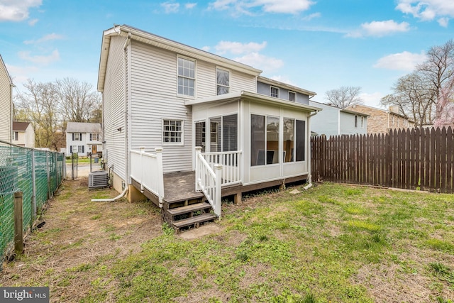 rear view of house with a sunroom, a yard, a fenced backyard, and central AC unit