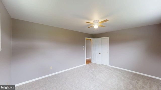 empty room with carpet floors, a ceiling fan, and baseboards
