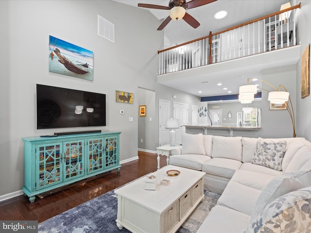 living area with wood finished floors, visible vents, a ceiling fan, and baseboards
