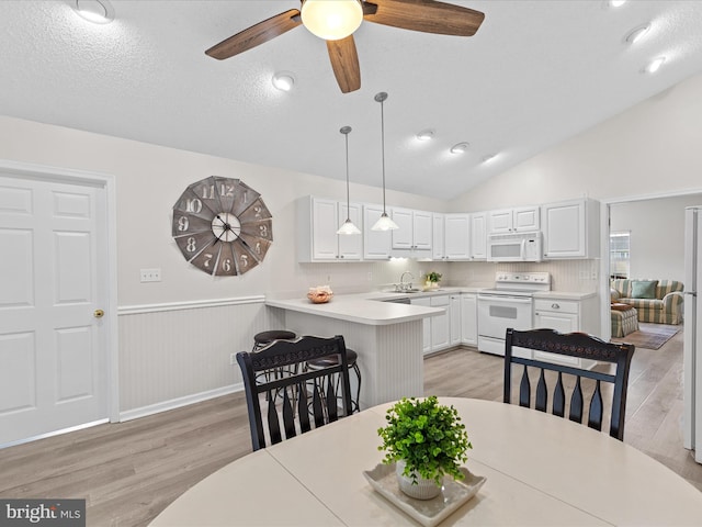 dining space with light wood-style flooring, lofted ceiling, ceiling fan, and wainscoting