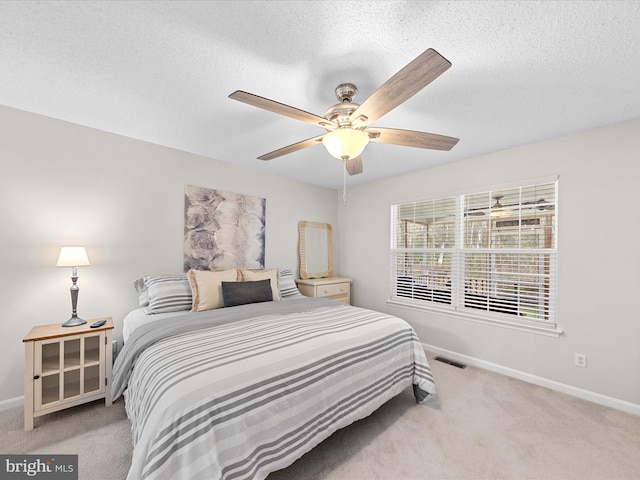 bedroom featuring baseboards, visible vents, a textured ceiling, and light colored carpet