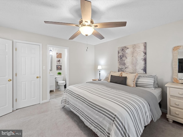 bedroom with a ceiling fan, ensuite bath, and light colored carpet
